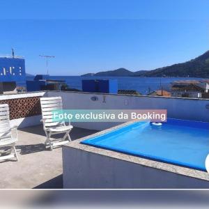 a swimming pool on the roof of a building with chairs at casa de praia ibicui in Mangaratiba