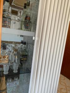 un armario de cristal con botellas de alcohol y vasos en Vila DLMeti, en Shkodër