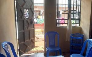ein Zimmer mit zwei blauen Stühlen und einer Tür mit einem Fenster in der Unterkunft Qyani Country Side Stay in Migori