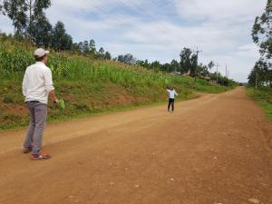 dos personas caminando por un camino de tierra con un frisbee en Qyani Country Side Stay, en Migori