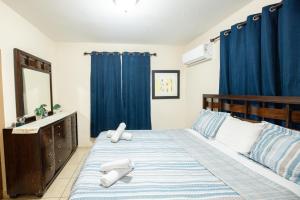 a bedroom with a bed with blue curtains and a sink at Arenales Vacational House in Isabela