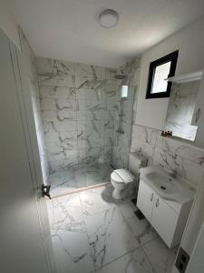 a white bathroom with a toilet and a sink at Family Bungalows in Ulcinj