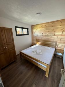 a large bed in a room with a wooden wall at Family Bungalows in Ulcinj