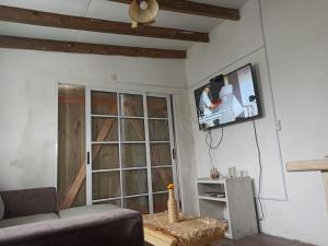 sala de estar con sofá y TV en la pared en Renapau2D, en La Paloma