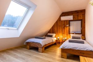 two beds in a attic room with a window at Apartmaji pri Dravi in Podvelka
