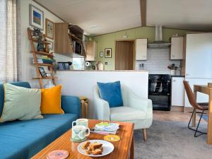 a living room with a blue couch and a table at Little Curlew, Ynyslas, Borth in Borth