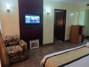 a bedroom with a bed and a tv and a chair at Equity resort hotel ijebu in Ijebu Ode