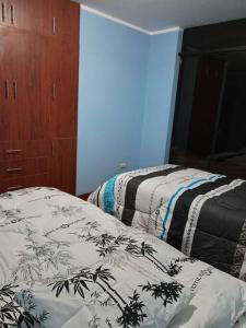 2 camas en una habitación con paredes azules en Departamento Cielo Cajamarquino, en Cajamarca