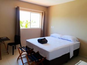 a room with a bed with two chairs and a window at Pousada Mangata in Maragogi