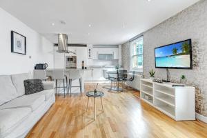 ロンドンにある2BR flat next to London Eye on lower marsh 96Aのリビングルーム(白いソファ付)、キッチンが備わります。