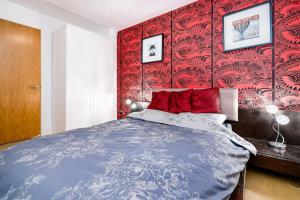 a bedroom with a bed with a red wall at 2BR flat next to London Eye on lower marsh 96A in London