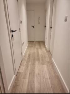 einen leeren Flur mit weißen Türen und Holzböden in der Unterkunft Beckenham - Luxury One Bedroom Apartment With Two Baths And WC in Elmers End