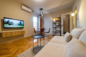 a living room with a couch and a tv on the wall at Apartman Nika in Pirot