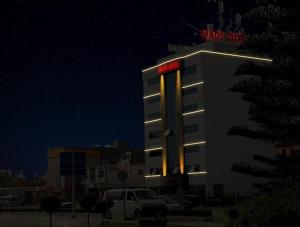 a building with a neon sign on top of it at Otel Madi in Seyhan