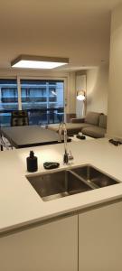 eine Küche mit einem Waschbecken und ein Wohnzimmer in der Unterkunft Vanbunnen in Knokke-Heist