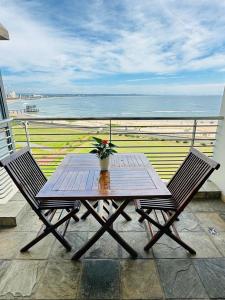 a wooden table and chairs on a balcony with the ocean at The Waves 905 Quayside Point in Durban