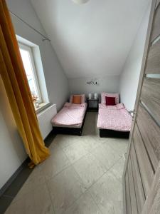 a attic room with two beds and a window at Apartamenty Świerkowa #1 in Ząbkowice Śląskie