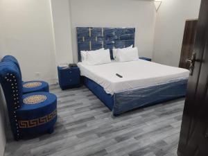 a bedroom with a bed and a blue chair at Safari Hotel in Lahore