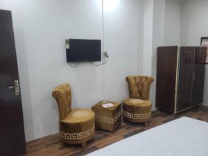 Safari Hotel في لاهور: غرفة بها كرسيين وتلفزيون على الحائط
