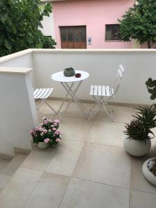 eine Terrasse mit einem Tisch, 2 Stühlen und Blumen in der Unterkunft Tom & Ros House in Casarano