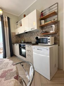 a kitchen with white cabinets and a microwave at Casa del sasso in Bergeggi