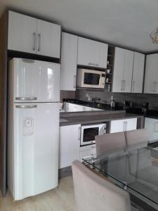 a kitchen with white cabinets and a white refrigerator at CASA NO BORGO MOBILIADA in Bento Gonçalves +8 photos