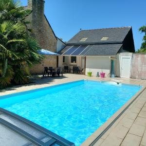 a large blue swimming pool in front of a house at Gite Les Sables Blancs in Plobannalec-Lesconil