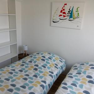 a bedroom with a bed and a painting of sailboats at Gite Les Sables Blancs in Plobannalec-Lesconil