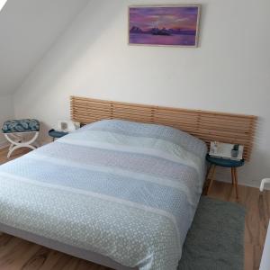 Gite Les Sables Blancs في Plobannalec-Lesconil: سرير في غرفة نوم مع صورة على الحائط