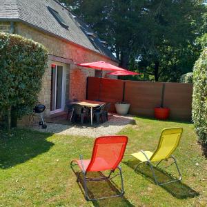 a yard with three chairs and a table with an umbrella at Gite Les Sables Blancs in Plobannalec-Lesconil
