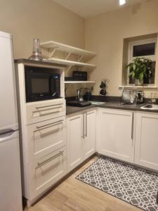 a kitchen with white cabinets and a microwave at Fort William, Dripsey 