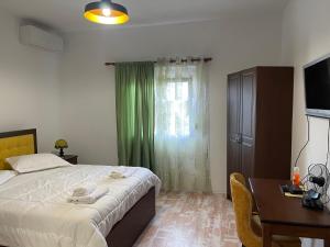 a bedroom with a bed and a desk and a window at Vila C++ in Berat