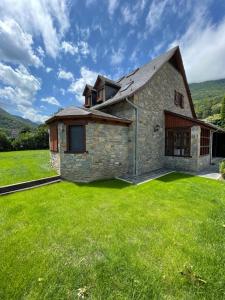 a stone house with a green lawn at Ca de Palomera Vall d’Aran in Les