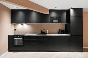 a kitchen with black cabinets and a black refrigerator at Cozy new apartment in Kristiansand