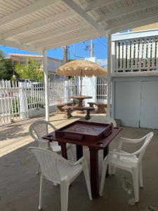 une table et des chaises en bois sur une terrasse avec un parasol dans l'établissement Cabanas Playa Santa/ Apto. A/ Swimming Pool/ Pool Table/ WIFI/ 3 min Beaches, à Guánica