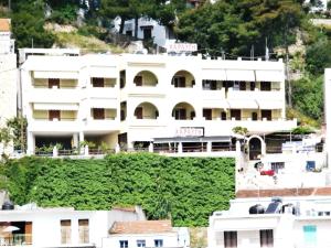 ein weißes Gebäude auf einem Hügel mit grüner Vegetation in der Unterkunft Haravgi Hotel in Patitiri