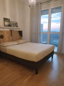 Ce lit se trouve dans une chambre dotée d'une grande fenêtre. dans l'établissement Appartamento con terrazzo privato Milano San Raffaele Linea verde, à Vimodrone