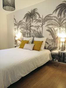 a bedroom with a white bed with palm trees on the wall at BLEU CASSIS-VINTAGE -3 Ch- Magnifique vue mer- Parking gratuit et Jardin in Cassis