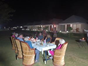 een groep mensen die 's nachts aan een tafel zitten bij Nature Resort & Camps - A Luxury Camps in Pushkar