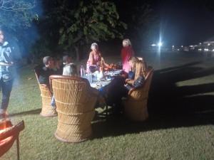 een groep mensen die 's nachts rond een tafel zitten bij Nature Resort & Camps - A Luxury Camps in Pushkar
