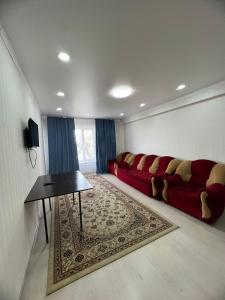 アルマトイにあるNureke Apartmentsの赤いソファとテーブルのあるリビングルーム