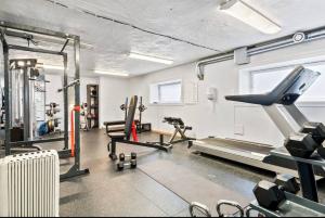 a gym with treadmills and machines in a room at Super cozy apartment in the heart of Bergen city in Bergen