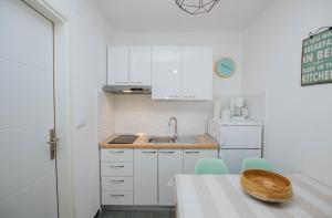 una pequeña cocina con armarios blancos y fregadero en Mamma mia apartments-city center, en Hvar
