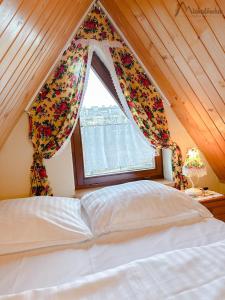 Schlafzimmer mit einem großen Bett und einem Fenster in der Unterkunft Willa Michałówka Attic in Zakopane