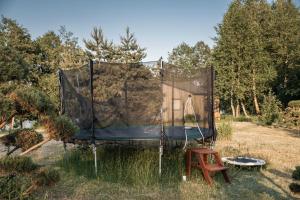 a net in the grass with a chair and a stool at Sodyba Gaižėnai in Vinkšnupiai