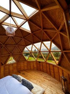 an attic room with a large window in a wooden building at Glamping Shalom in Choachí