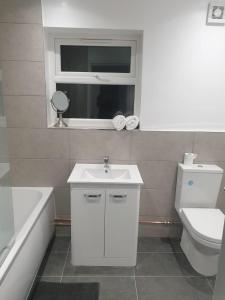 een badkamer met een wastafel, een toilet en een raam bij SWEET DREAMS 2 in Luton