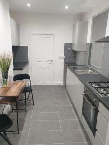 a kitchen with white cabinets and a table and a sink at SWEET DREAMS 2 in Luton