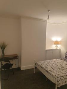 a bedroom with a bed and a desk and a lamp at SWEET DREAMS 2 in Luton