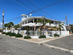 een wit gebouw met een wit hek en palmbomen bij Cabanas Playa Santa/ Apto. A/ Swimming Pool/ Pool Table/ WIFI/ 3 min Beaches in Guanica